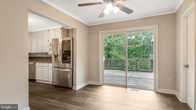 unfurnished dining area featuring dark wood-style flooring, ornamental molding, ceiling fan, and baseboards