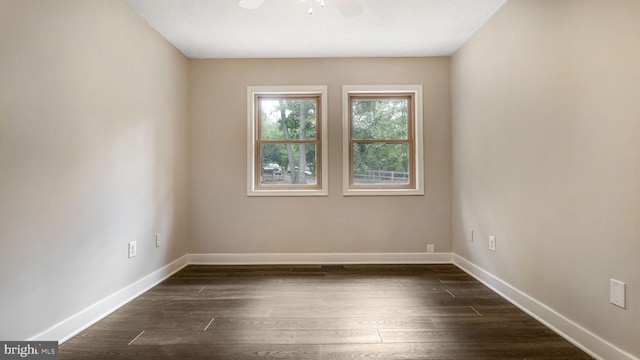 spare room featuring baseboards, dark wood finished floors, and ceiling fan