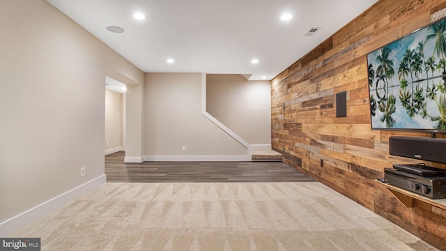 finished below grade area with carpet, recessed lighting, baseboards, wood finished floors, and wood walls