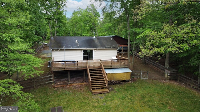 back of property with stairs, a deck, and a wooded view