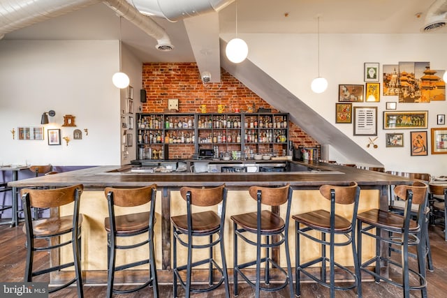 indoor wet bar with brick wall and dark wood-style flooring