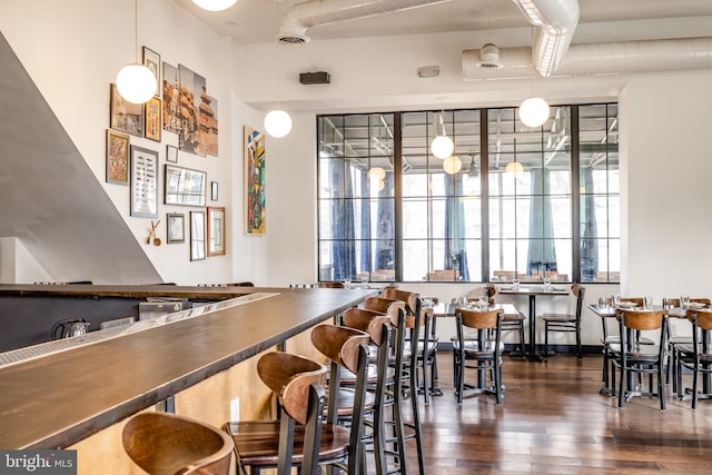 bar area featuring dark wood finished floors and hanging light fixtures