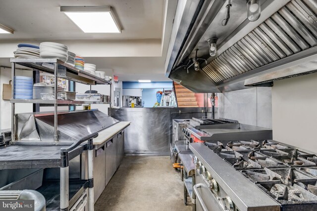 kitchen featuring finished concrete flooring, high end stainless steel range oven, and ventilation hood