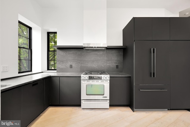kitchen with stainless steel gas range oven, paneled built in fridge, backsplash, modern cabinets, and dark cabinets