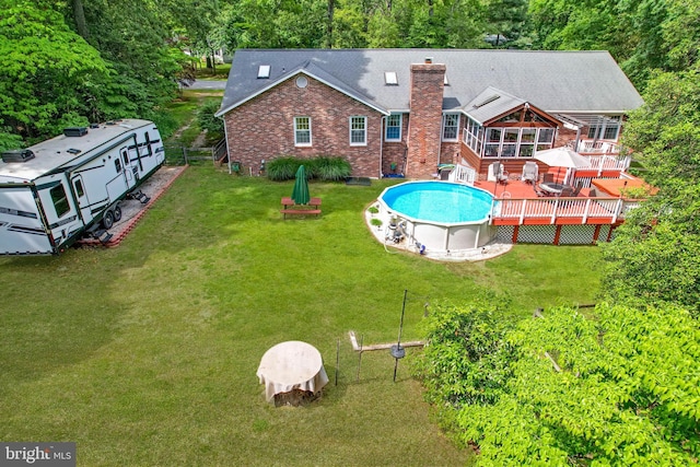 9180 Rolling Meadow Run, Pasadena, MD 21122 - rear view of property with brick siding, a wooden deck, an outdoor pool, a chimney, and a yard