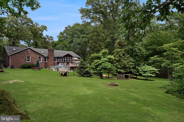9180 Rolling Meadow Run, Pasadena, MD 21122 - view of grassy yard featuring an outdoor fire pit and a wooden deck