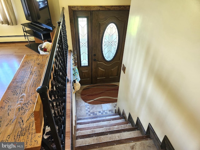 foyer entrance featuring stairway, wood finished floors, and baseboard heating