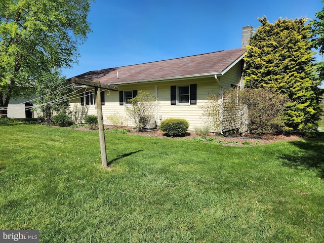 exterior space with a chimney and a lawn