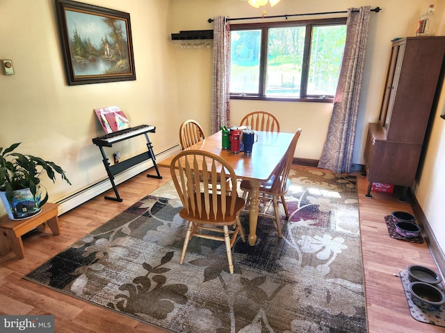 dining area with baseboards, baseboard heating, and wood finished floors