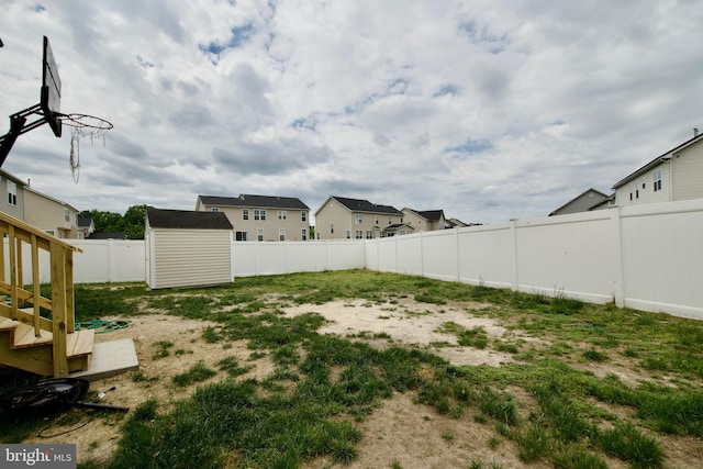 fenced backyard featuring an outbuilding, a storage unit, and a residential view