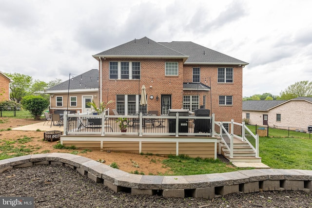 rear view of house with an outdoor fire pit, brick siding, a wooden deck, and a shingled roof