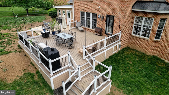 deck featuring outdoor dining space, stairway, and a yard