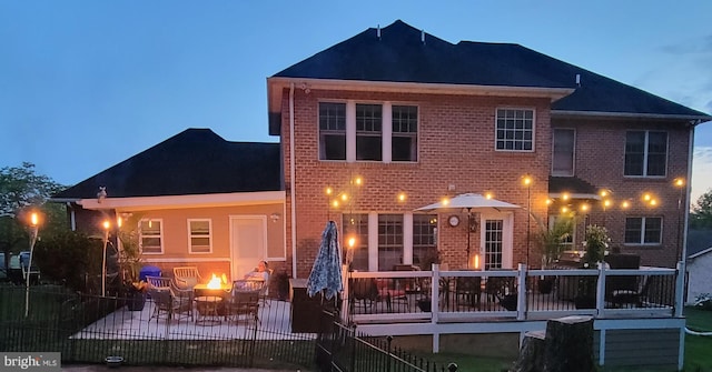 back of house with an outdoor fire pit, brick siding, and a patio area