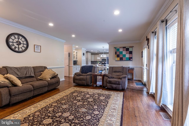 living room featuring dark wood-style flooring, recessed lighting, ornamental molding, baseboards, and a chandelier