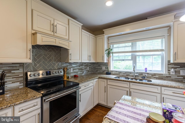 kitchen featuring stainless steel electric stove, a sink, tasteful backsplash, dark wood-style floors, and light stone countertops