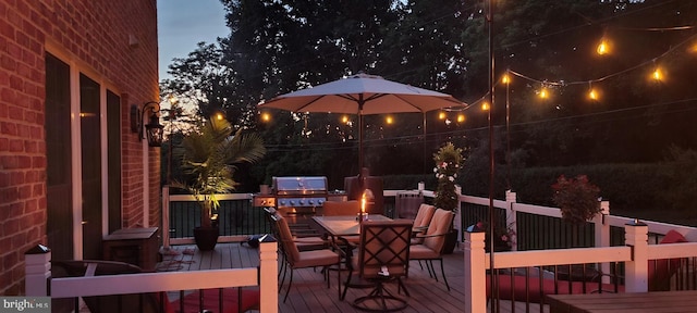 deck at night featuring outdoor dining area and grilling area