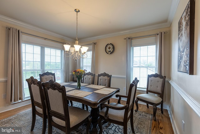 dining room with a chandelier, ornamental molding, and wood finished floors