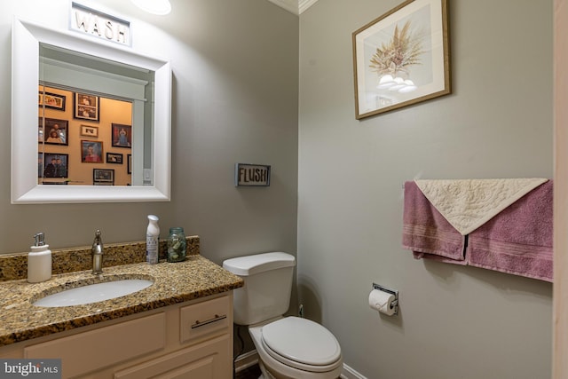 bathroom with toilet, vanity, crown molding, and baseboards