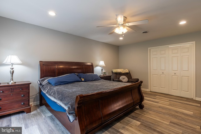 bedroom with wood finished floors, baseboards, a ceiling fan, a closet, and recessed lighting
