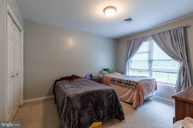 carpeted bedroom featuring baseboards and a closet