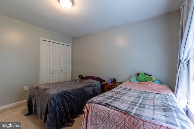 carpeted bedroom with a closet and baseboards