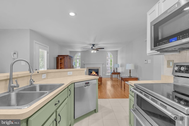 5620 Nutwell Sudley Rd, Deale, MD 20751 - kitchen featuring green cabinets, stainless steel appliances, a sink, a ceiling fan, and a lit fireplace