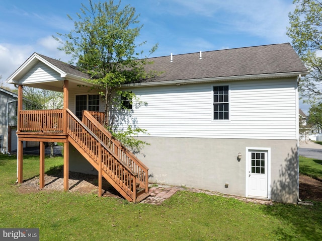 back of property with a shingled roof, a yard, and stairs