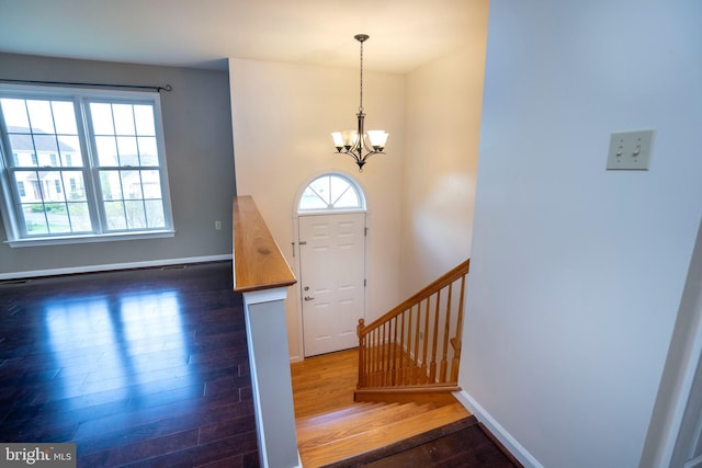 foyer entrance featuring stairs, wood finished floors, baseboards, and a notable chandelier