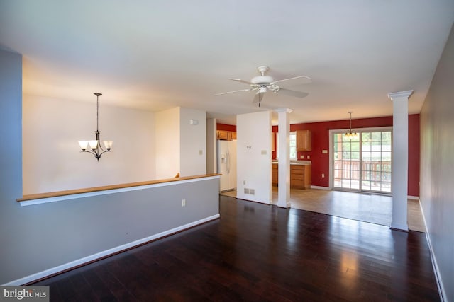 unfurnished living room featuring baseboards, ceiling fan with notable chandelier, decorative columns, and wood finished floors