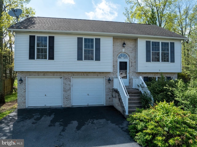 bi-level home featuring driveway, brick siding, and an attached garage