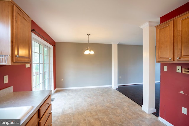 kitchen with baseboards, brown cabinets, a notable chandelier, and light countertops