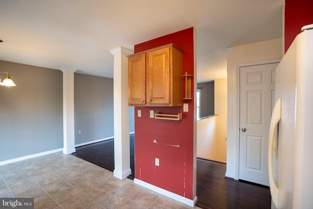 kitchen with freestanding refrigerator, baseboards, and brown cabinetry