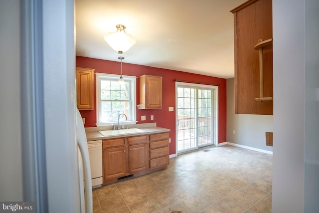kitchen featuring a sink, baseboards, decorative light fixtures, light countertops, and white dishwasher