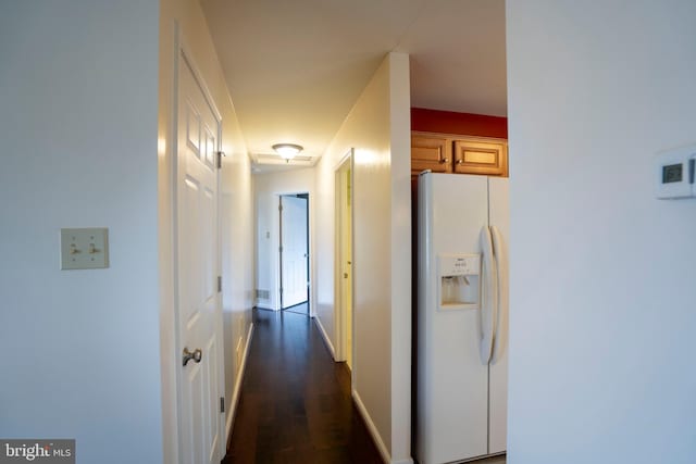 corridor with dark wood-style flooring and baseboards