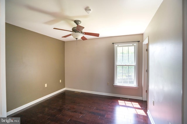 unfurnished room with baseboards, dark wood finished floors, ceiling fan, and visible vents