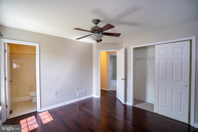 unfurnished bedroom featuring ensuite bathroom, a closet, visible vents, wood-type flooring, and baseboards