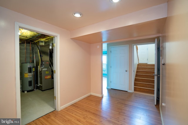 entrance foyer featuring water heater, light wood-type flooring, stairway, and baseboards