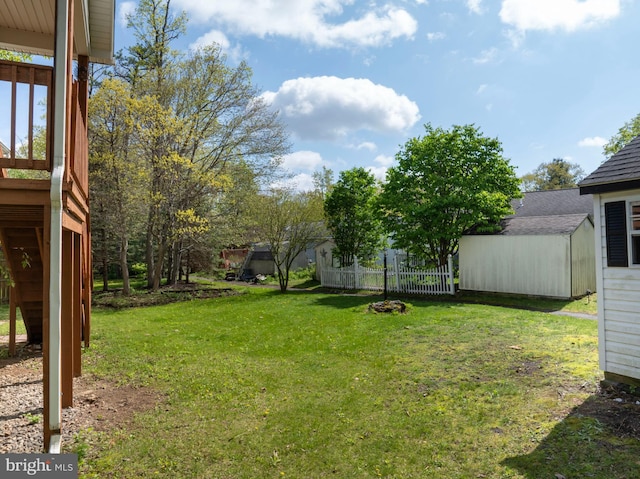 view of yard featuring fence, a storage shed, and an outbuilding