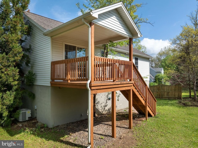 back of house with central air condition unit, fence, a deck, a lawn, and a shingled roof