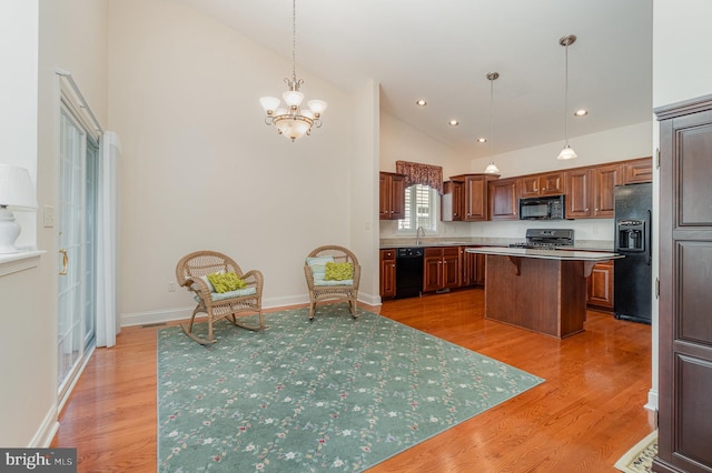 kitchen with black appliances, a kitchen island, high vaulted ceiling, a kitchen bar, and a chandelier