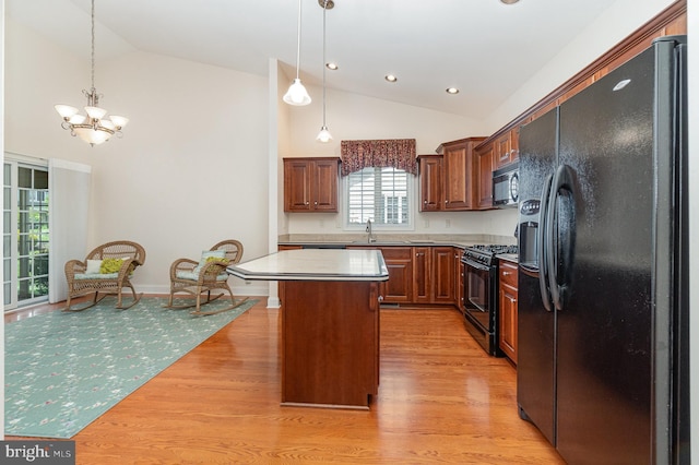 kitchen featuring black appliances, a sink, a chandelier, a kitchen island, and light wood-style floors