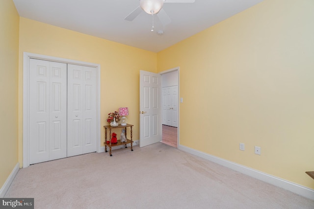 bedroom with light colored carpet, a closet, baseboards, and a ceiling fan