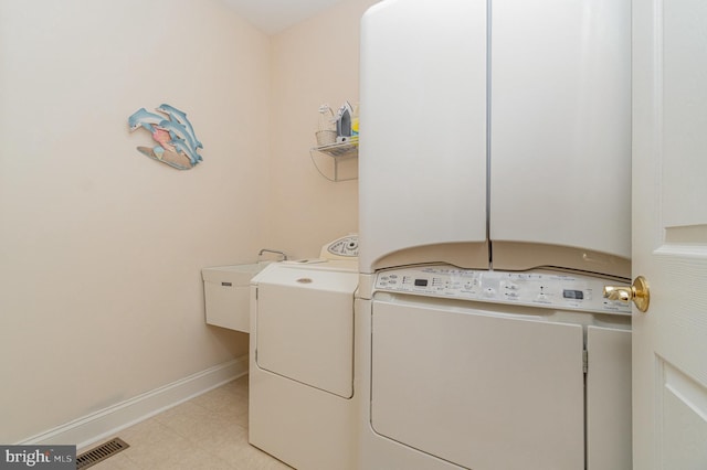 laundry area with washing machine and clothes dryer, baseboards, and light tile patterned flooring