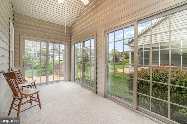 sunroom / solarium with vaulted ceiling, plenty of natural light, and carpet flooring