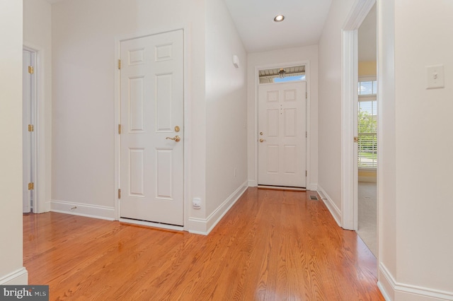hall featuring light wood-style flooring, baseboards, and recessed lighting