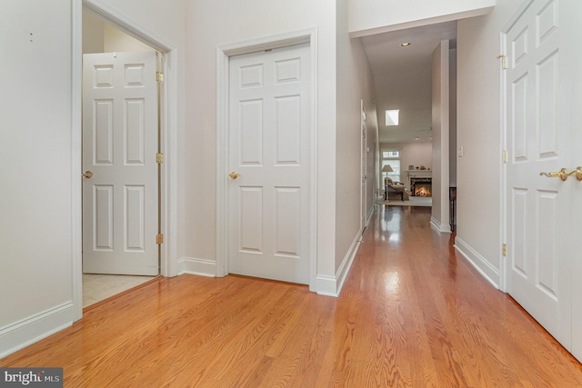 hallway with light wood-type flooring and baseboards