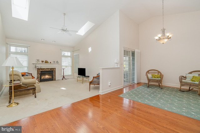 sitting room featuring a skylight, high vaulted ceiling, a high end fireplace, healthy amount of natural light, and wood finished floors