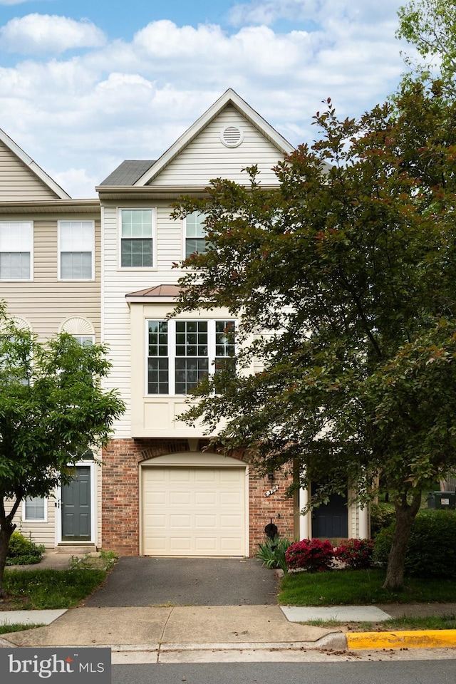 view of property featuring brick siding, driveway, and a garage