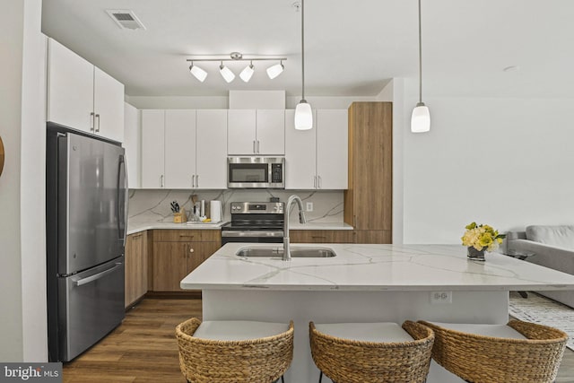 10755 Fairgrounds Dr Unit 320, Fairfax, VA 22030 - kitchen with appliances with stainless steel finishes, a sink, dark wood-type flooring, hanging light fixtures, and a breakfast bar area