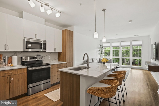 10755 Fairgrounds Dr Unit 320, Fairfax, VA 22030 - kitchen featuring appliances with stainless steel finishes, a sink, dark wood-type flooring, backsplash, and a kitchen bar